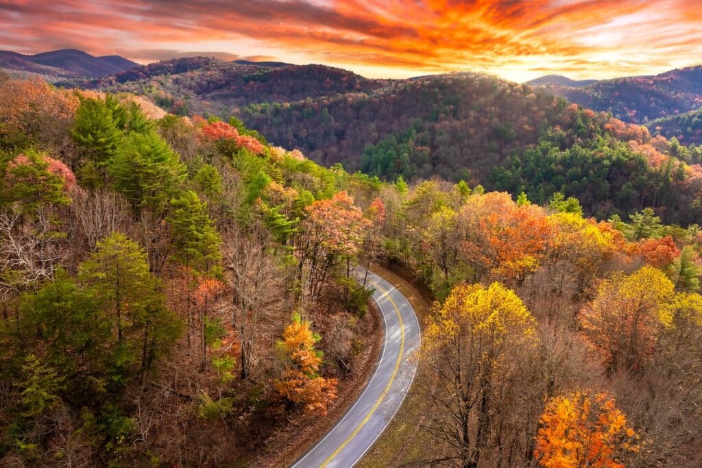 Your Guide to the Blue Ridge Parkway Near Asheville 1 Vibrant autumn landscape in North Carolina mountains. Fall colors stretch across hillsides along quiet mountain road on the Blue Ridge Parkway.