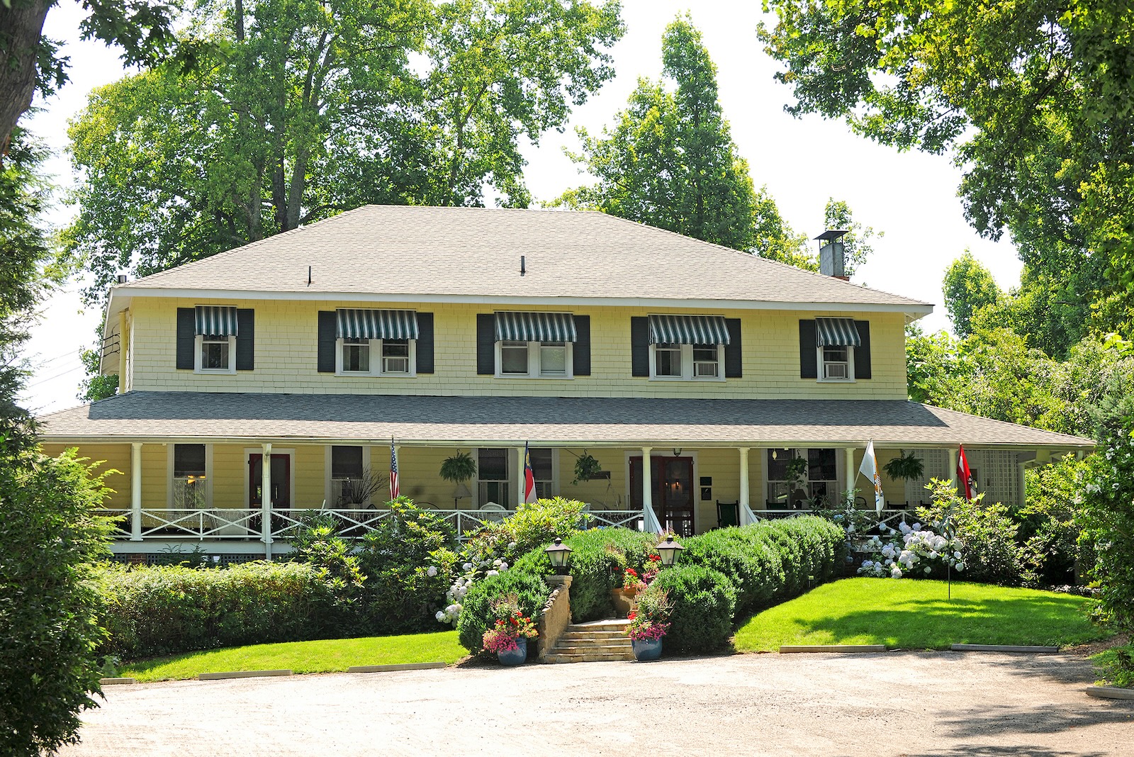 North Carolina Wineries We Send Our Guests To 3 A yellow two-story building framed by trees, showcasing the best bed and breakfast NC mountains.