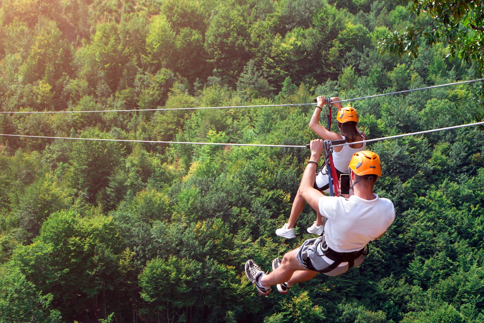 A man and woman zip lining among the trees, one of the top things to do in Saluda NC.