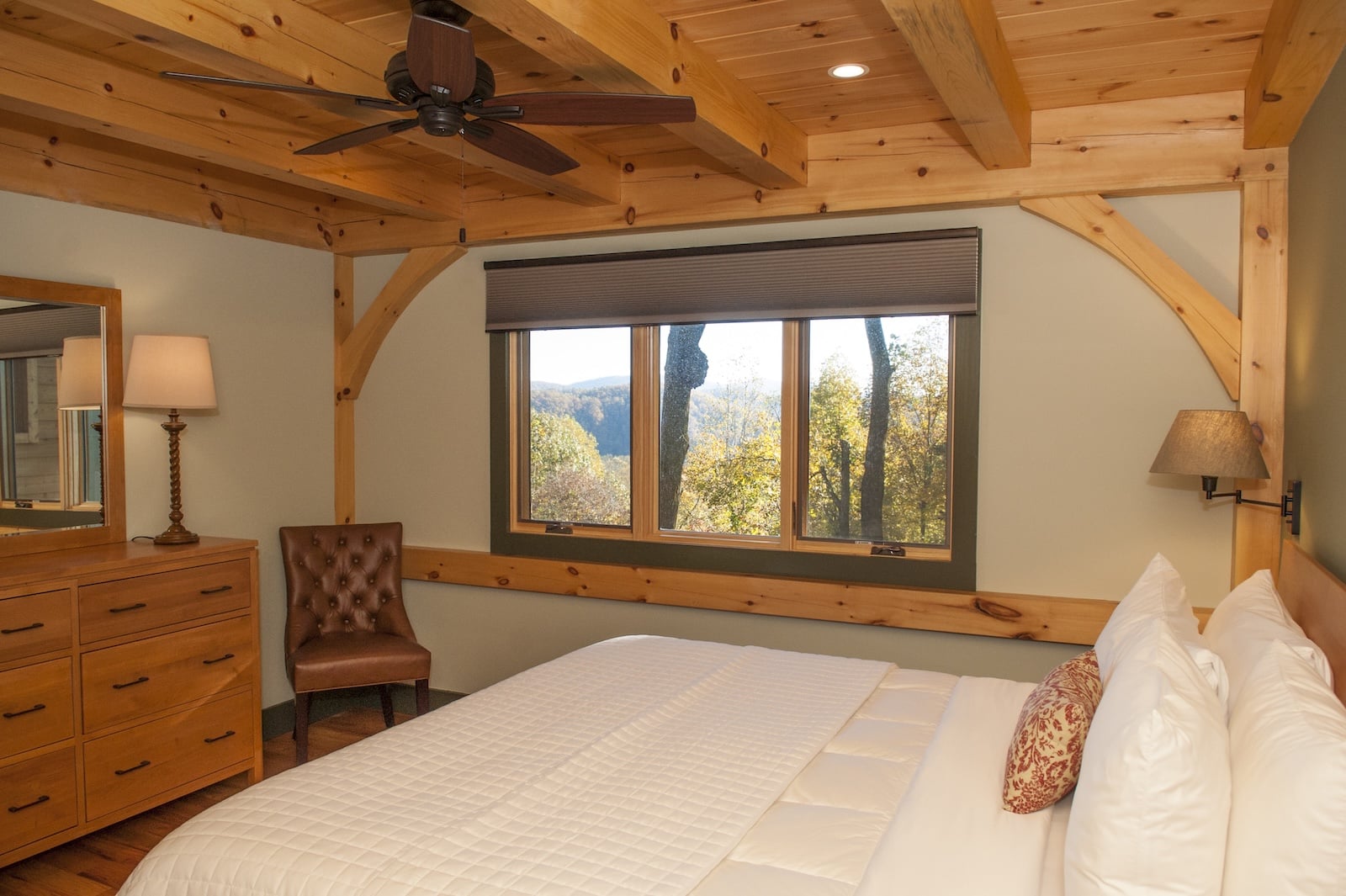 The Best North Carolina Mountain Towns to Explore 3 A guest suite, featuring a bed and dresser with a window with mountain vies at a Bed and Breakfast in NC.